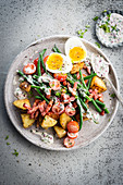 Sauted potato salad with bacon, green beans, cherry tomatoes and hard-boiled egg