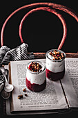 Compote of berries with yogurt and granola in jars on open book