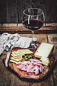 Holzbrett mit Aufschnitt, Käse und einem Glas Rotwein