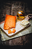 English cheese, crackers and a glass of whisky on wooden board