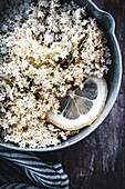 Prepare elderflower syrup: elderflowers with lemon slices in a saucepan