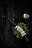 Raw cod skewer on sprouts