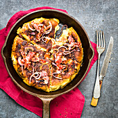 Spicy bacon, onions, and reblochon frittata baked in a cast iron pan