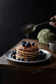 Gestapelte Pancakes mit Blaubeeren, Brombeeren und Honig