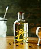 Weißer Rum mit Zitronenzesten und Gewürznelken in Glasflasche
