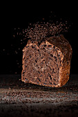 Schokoladenstreusel fallen auf angeschnittenes Kakao-Schokoladenbrot