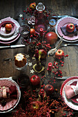 Weihnachtlich gedeckter Tisch dekoriert mit Beerenzweigen, Äpfeln und Kerzen