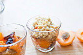 Preparing apricot crumble: layering ingredients in dessert glasses