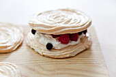 Preparing meringues with red fruit and whipped cream