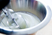 Whisking egg whites in a metal bowl until stiff