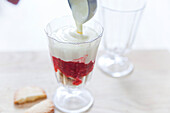 Preparing raspberry tiramisu: layering ingredients in glasses