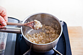 Sautéing onions to make mini potato gratin with prawns in cream sauce