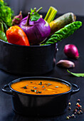 Vegetable soup with fresh vegetables in the background