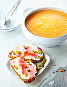 Cream of vegetable soup and bread with cream cheese, ham and gherkins