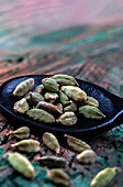 Cardamom seeds on a black wooden spoon