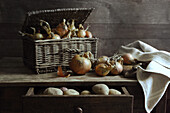 Zwiebeln im Korb und Kartoffeln in Tischschublade
