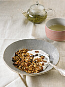 Muesli with dried fruits and chocolate mixed with curd cheese and a cup of green tea