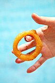 Hand holding a fried onion ring
