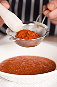 Preparing a Romanesco sauce - Straining the sauce through a sieve