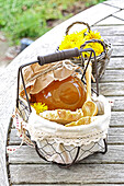 A glass of dandelion jelly with bread in wire baskets on an outdoor table