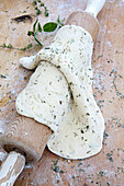 Dough rolled out for a savory tart or pie with herbs on a rolling pin