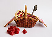 Himbeertörtchen und Löffel in Miniatur-Picknickkorb