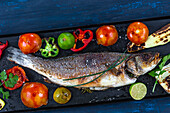 Sea bass on a plancha cooking among vegetables
