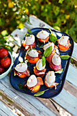 Melon skewers with Serrano ham and mozzarella as aperitifs on an outdoor table