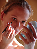 Young woman applying make up