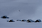 Skier and snow-covered cabins, Alps, Europe