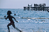 Running boy and people on jetty, beachlife, Halland, Sweden