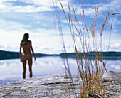 Woman standing at the waters edge, lake shore, Sweden