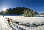 Two mountain bikers in the snow, Upper Bavaria, Germany