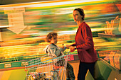 Mother with child and shopping kart in supermarket