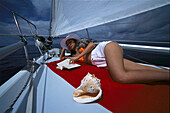 Frau liest ein Buch, Segelschiff Pebbles, Puerto de Mogán, Gran Canaria, Kanarische Inseln, Spanien