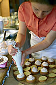 Eine Frau füllt Muffins in einer Bäckerei