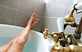 Beine einer badenden Frau in der Badewanne in einer Altbauwohnung, Wien, Österreich