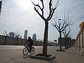 Ein Mann fährt mit dem Fahrradauf der Strasse, Shanghai, China