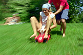 Young man pushing young woman on a toy car