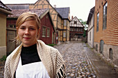Junge Frau in traditioneller Kleidung neben dem Freilichtmuseum Norsk Folkemuseum, Norsk Folkemuseum, Oslo, Norwegen