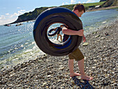 Teenager with rubber ring, inflatable tyre, on the beach at Lulworth Cove, South England, Great Britain