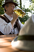 Older Bavarian man drinking beer in beer garden, Munich, Bavaria
