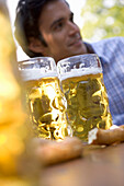 Three beer steins against face of young man, Munich, Bavaria