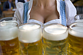 Young waitress with beer steins in beer garden, Munich, Bavaria