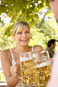 Junges Paar im Biergarten beim Anstoßen, Starnberger See, Bayern, Deutschland