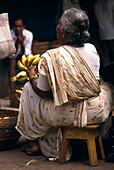 Ältere Frau verkauft Bananen auf dem Markt, Mapusa, Goa, Indien