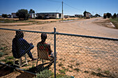 Zwei Personen sitzen am Straßenrand, Simpson Desert, Queensland, Australien