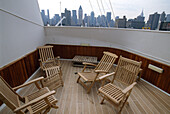 Chairs on the deck of the cruise ship Queen Elizabeth 2 and the skyline of Manhattan