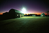 Buildings and a deserted clearance at sunset, Quonset Hut, Wooleen Station, Australia