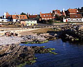 Menschen an einem Kieselstrand und die Häuser von Gudhejm, Nordküste, Bornholm, Dänemark
